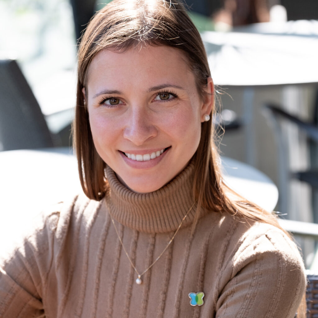 Arlene Miron Woman in burgundy turtleneck sweater with pendant necklace and Kidney Cancer Canada pin - Arlene Miron.