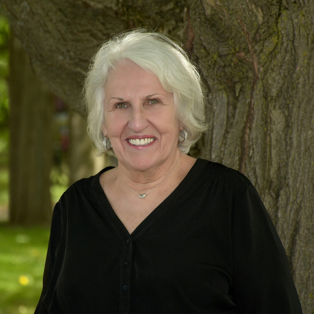 Karen Ross Woman in black shirt standing in front of tree - Karen Ross.