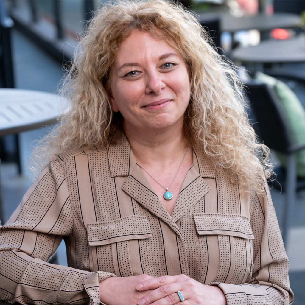 Staff_ Mona Awad Woman with striped and dotted burgundy shirt smiling - Mona Awad.